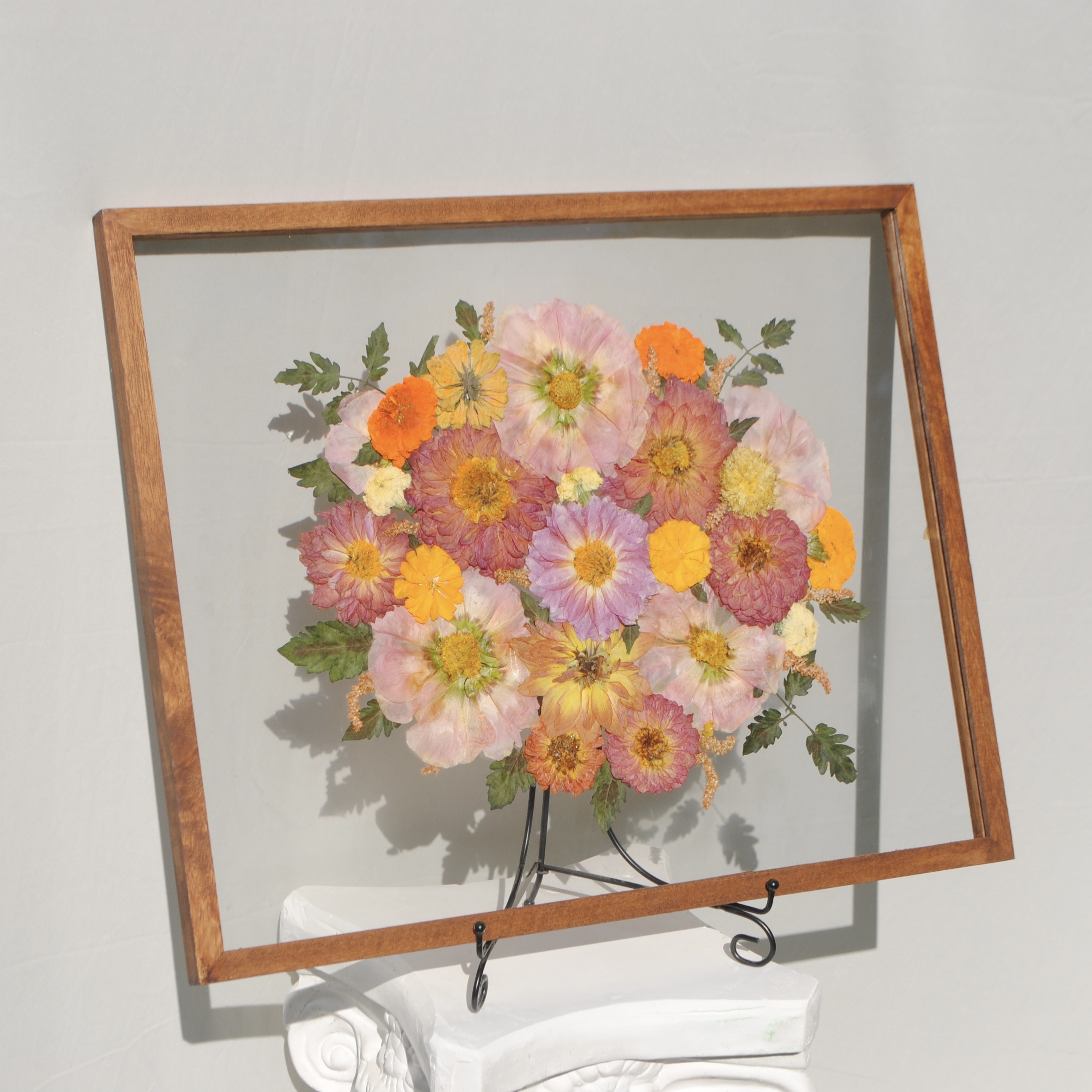 Pink and yellow pressed flowers beautifully arranged in a wooden frame for step two