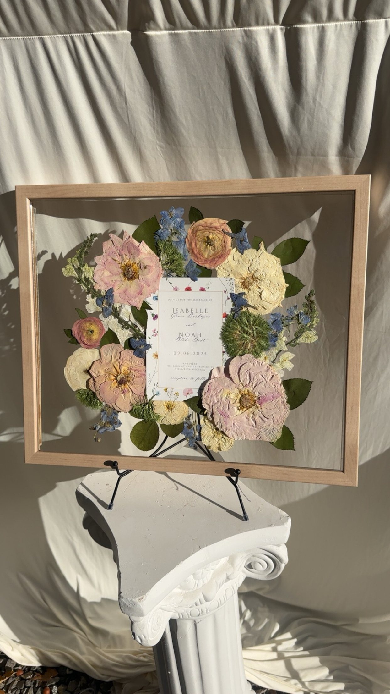 A wedding invitation framed and surrounded by pressed flowers